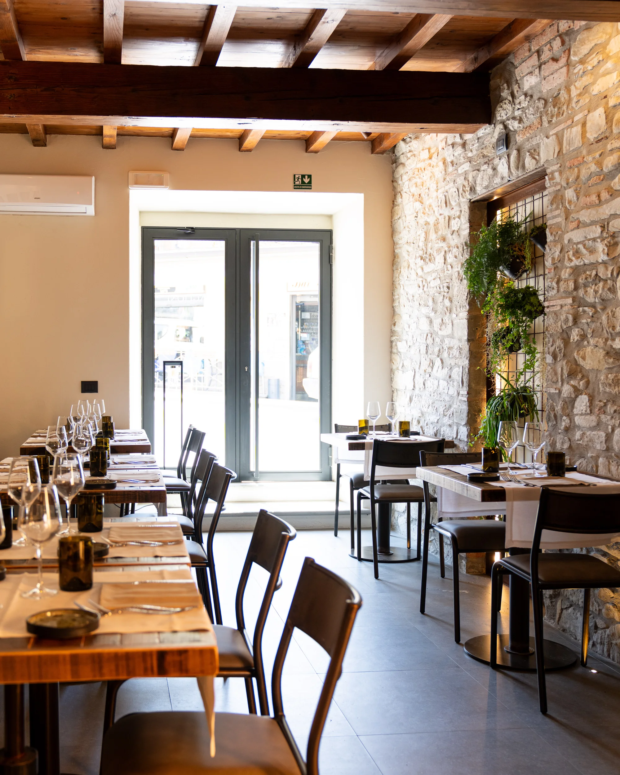 Tavoli apparecchiati e pareti in pietra dell’Osteria Baglioni